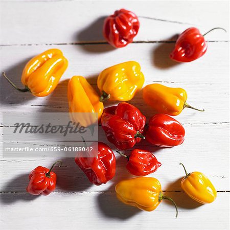 Red and yellow mini peppers on a white wood surface (top view)