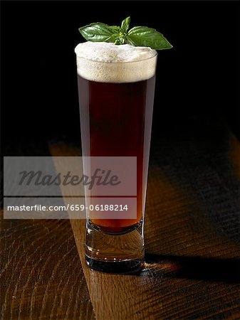 Tall Glass of Amber Beer with a Basil Garnish Tall Glass of Amber Beer with a Basil Garnish