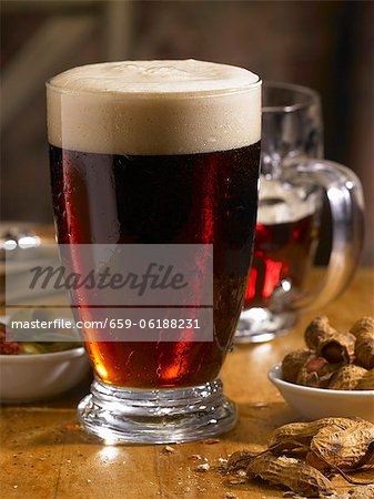 Dunkles Bier auf einem Tisch mit Nüssen und Oliven Dunkles Bier auf einem Tisch mit Nüssen und Oliven