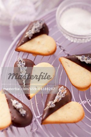 Heart-shaped biscuits decorated with chocolate icing and candied lavender flowers