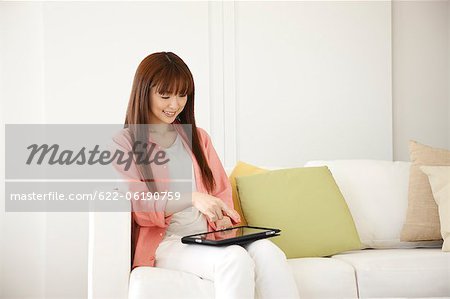 Jeune femme se détendre sur le canapé et l'utilisation de poche
