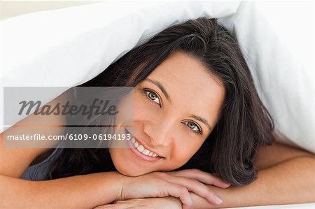 Close-up of woman with green eyes under a duvet