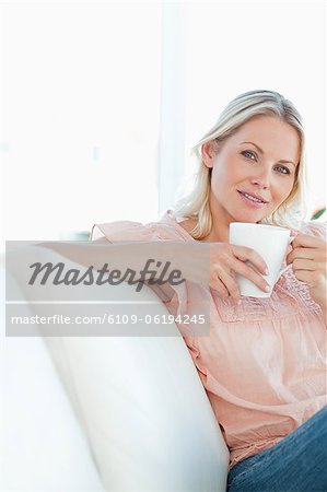 Smiling  blonde female sitting on her sofa