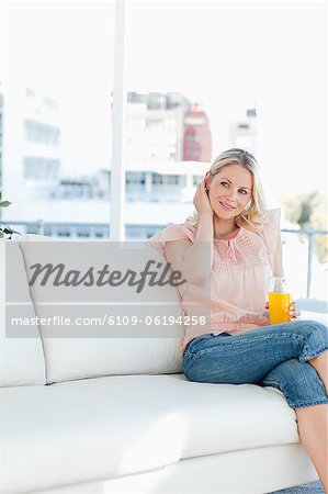 Femme blonde, souriante avec un verre de jus d'orange