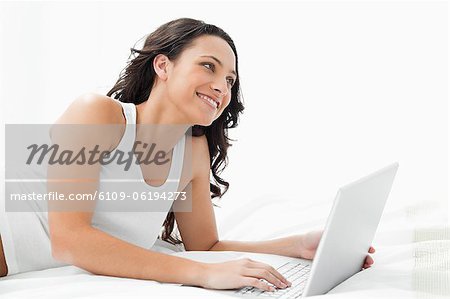Junge Frau mit ihrem Laptop auf ihrem Bett