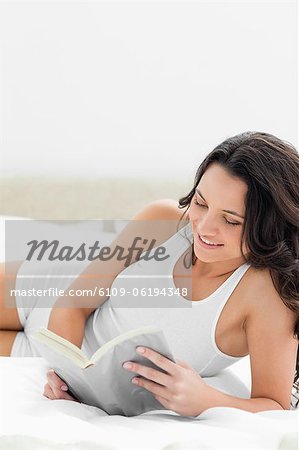 Close-up of a sexy woman reading a book on her bed