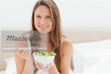 Young woman smiling while eating a salad