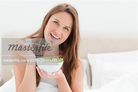 Cute woman smiling while eating a salad