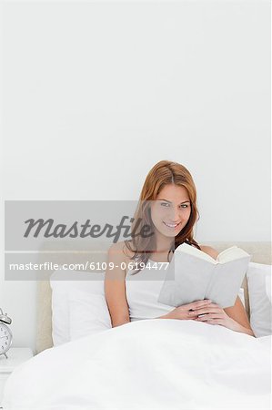 Portrait of a redheaded smiling while reading a book