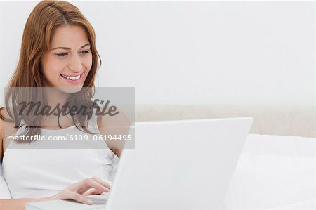 Femme rousse souriant tout en utilisant un ordinateur personnel