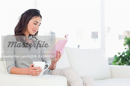 Young woman reading a book with a coffee