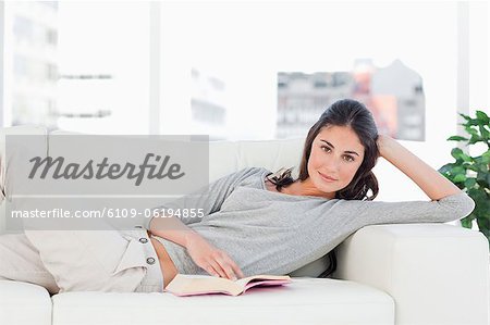 Portrait of a brunette reading on her sofa