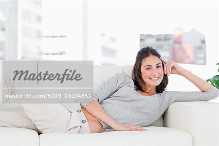 Portrait d'une brune heureuse sur son canapé