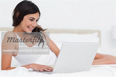 Smiling brunette using her laptop