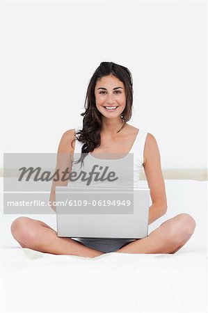 Brunette on her bed with a laptop