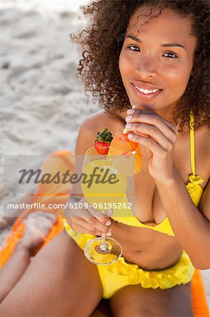 Junge Frau beim Trinken eines exotischen Cocktails in die Kamera schaut