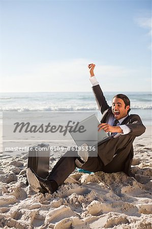 Homme d'affaires soulevant une jambe et un bras tout en étant assis sur la plage
