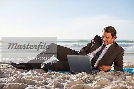 Homme d'affaires souriant couché sur le côté de la plage