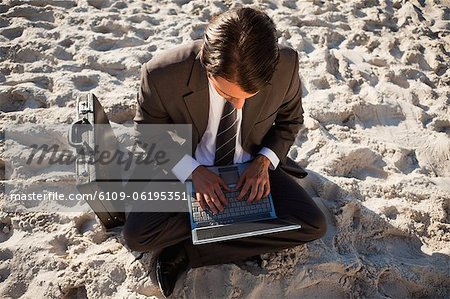 Vue aérienne d'un homme d'affaires jeune assis les jambes croisées sur la plage