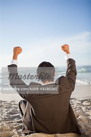 Rear view of a young businessman raising his arms