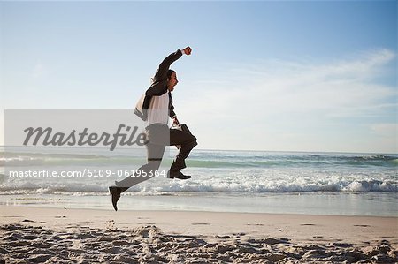 Successful businessman jumping on the beach