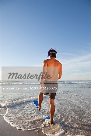 Young man wearing a snorkeling equipment while walking in the water