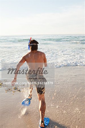 Junger Mann läuft im Wasser mit Flossen