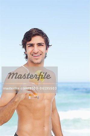 Man looking ahead and smiling while holding a cocktail