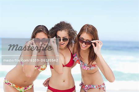 Trois femmes souriant heureusement tout en admirant leurs lunettes de soleil