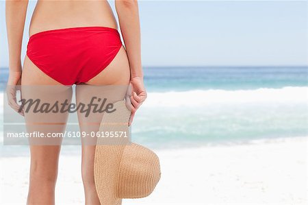 Woman holding a hat against her right leg