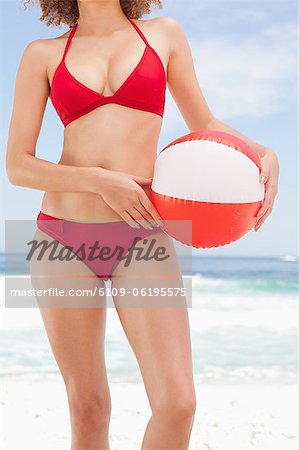 Femme en bikini tient un ballon de plage contre la hanche