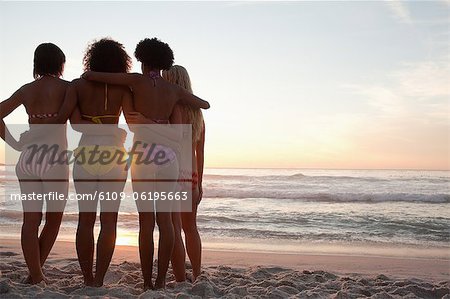 Four friends holding each other while watching the horizon