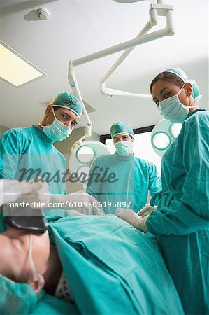 High view of a surgical team operating while looking at camera