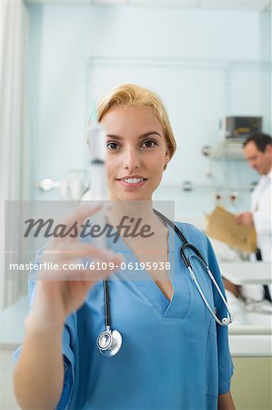 Blonde Krankenschwester eine Spritze beim Blick in die Kamera halten