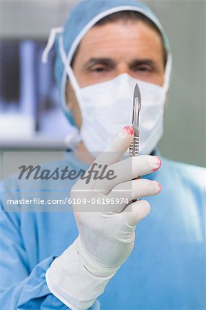 Chirurg Skalpell in seiner behandschuhten Hand haltend
