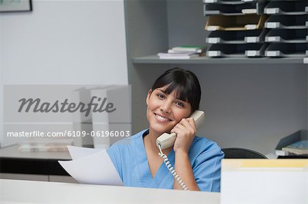 Nurse smiling while phoning and holding paper