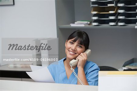 Infirmière souriant tout en téléphonant et en tenant le papier