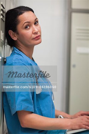 Female surgeon sitting in a locker room with a laptop