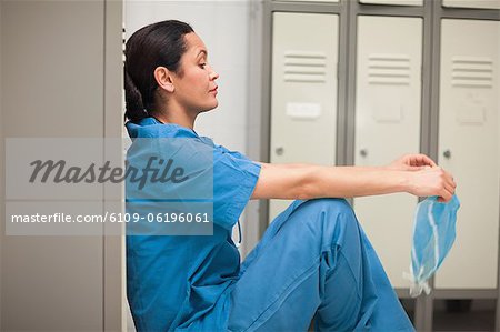 Thinking female surgeon sitting in a locker room