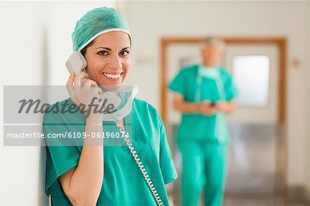 Smiling surgeon standing in a hallway while holding a phone
