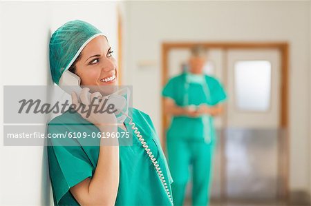 Happy surgeon standing in a hallway while holding a phone