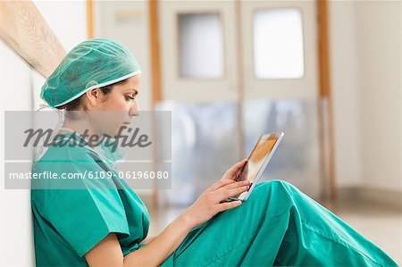 Female surgeon sitting on a hallway while holding a tactile tablet