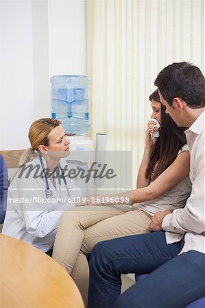 Arzt im Gespräch mit einer weinenden Frau in einem Warteraum