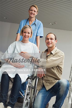 Pregnant woman in a wheelchair with a nurse and a man