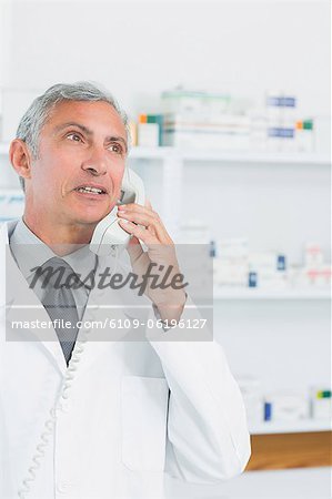 Pharmacist standing in a pharmacy while telephoning