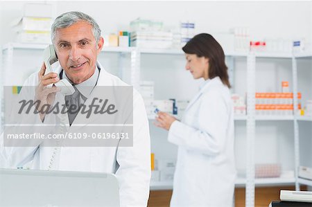 Apotheker am Telefon in einer Apotheke mit einem anderen Apotheker