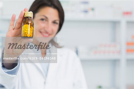 Female pharmacist showing pills and standing in a pharmacy
