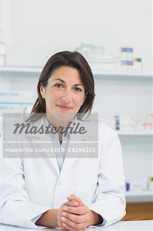 Female pharmacist behind a counter joining his hands