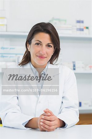 Pharmacien de femme derrière un comptoir en joignant ses mains