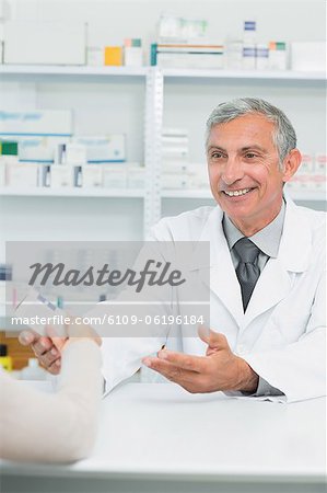 Pharmacien mâle heureux, donnant un boîte de pilules à un client